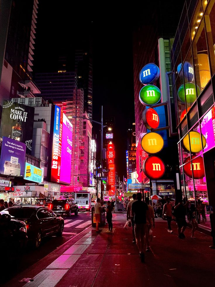 people are walking on the sidewalk in front of tall buildings with neon signs at night