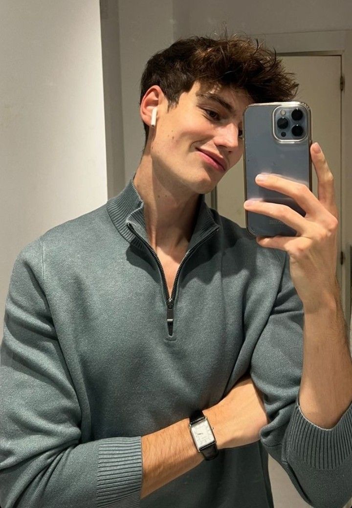 a young man taking a selfie with his cell phone in front of the mirror