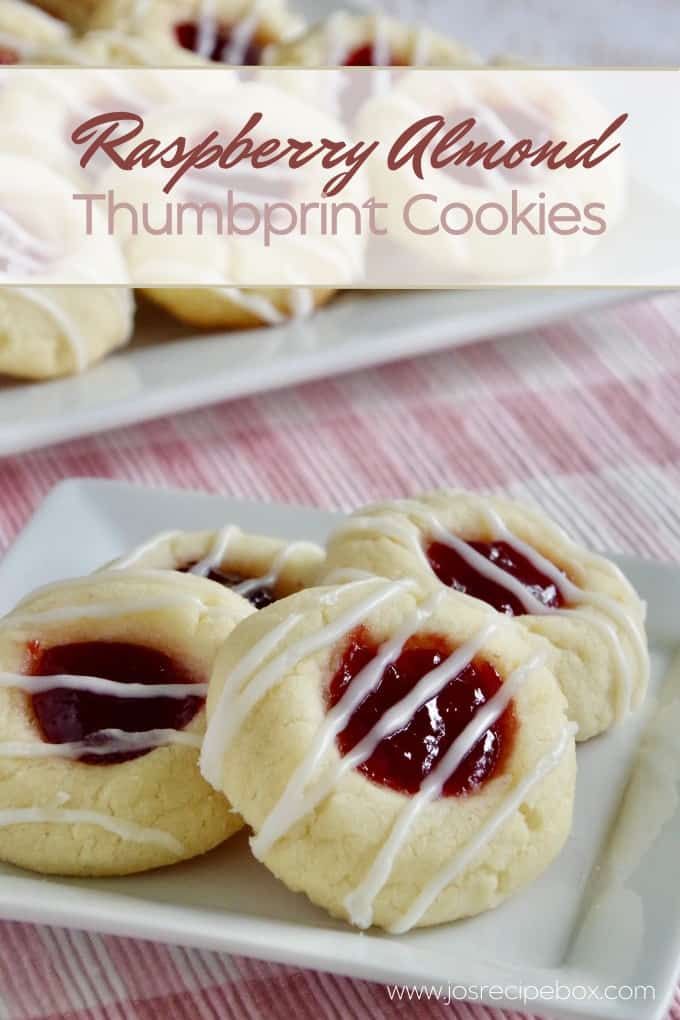 raspberry almond thumbprint cookies on a white plate with pink and red table cloth