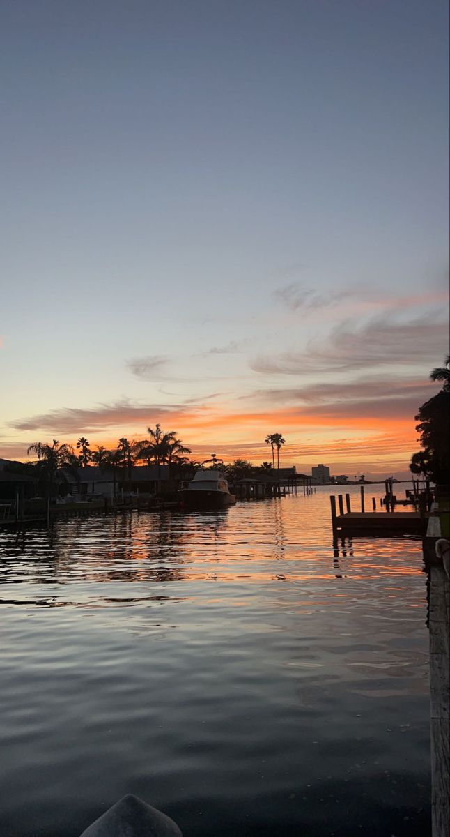 the sun is setting over the water and boats are docked