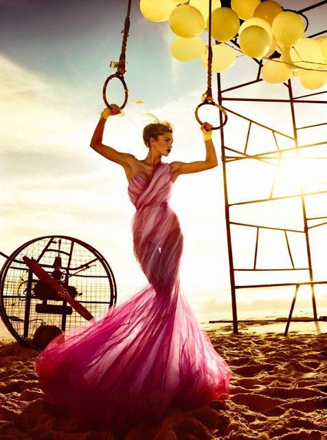 a woman in a long pink dress holding two hoop rings