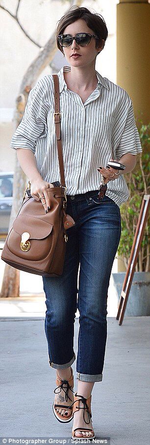 a woman walking down the street carrying a brown purse