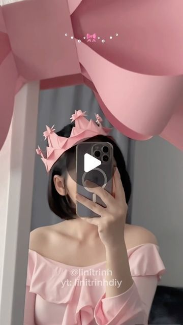 a woman taking a selfie with her cell phone wearing a pink dress and tiara