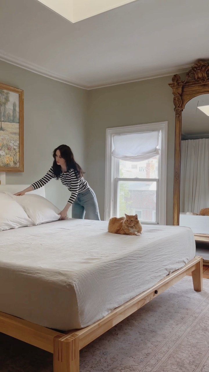 a woman standing on top of a bed next to a cat