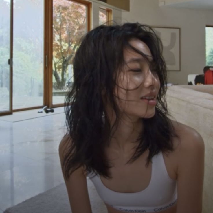 a woman with wet hair is sitting on the floor in front of a living room