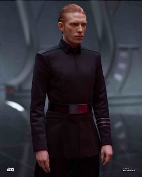 a man with red hair in a star wars uniform looking at the camera while standing