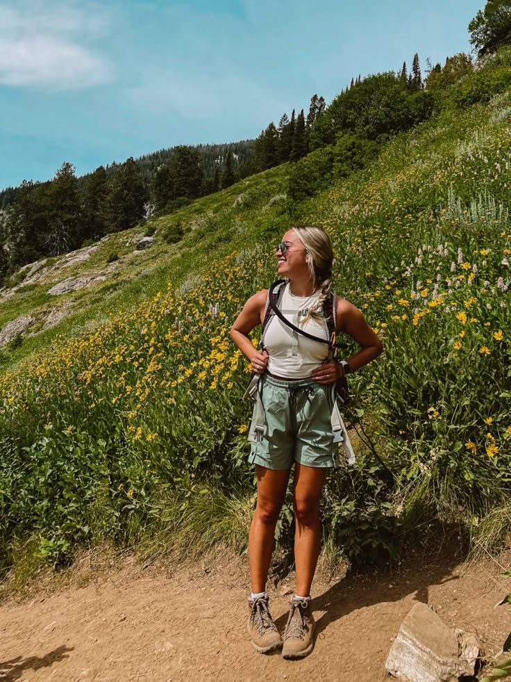 a woman standing on top of a lush green hillside