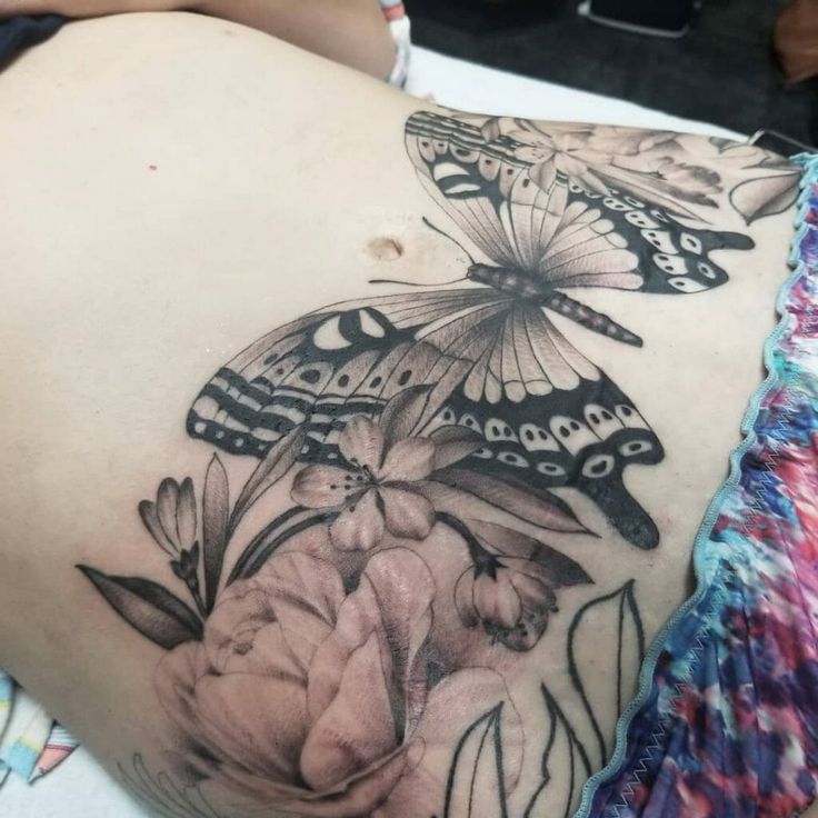 a woman's stomach with butterflies on it and flowers in the back, as well as an image of a flower