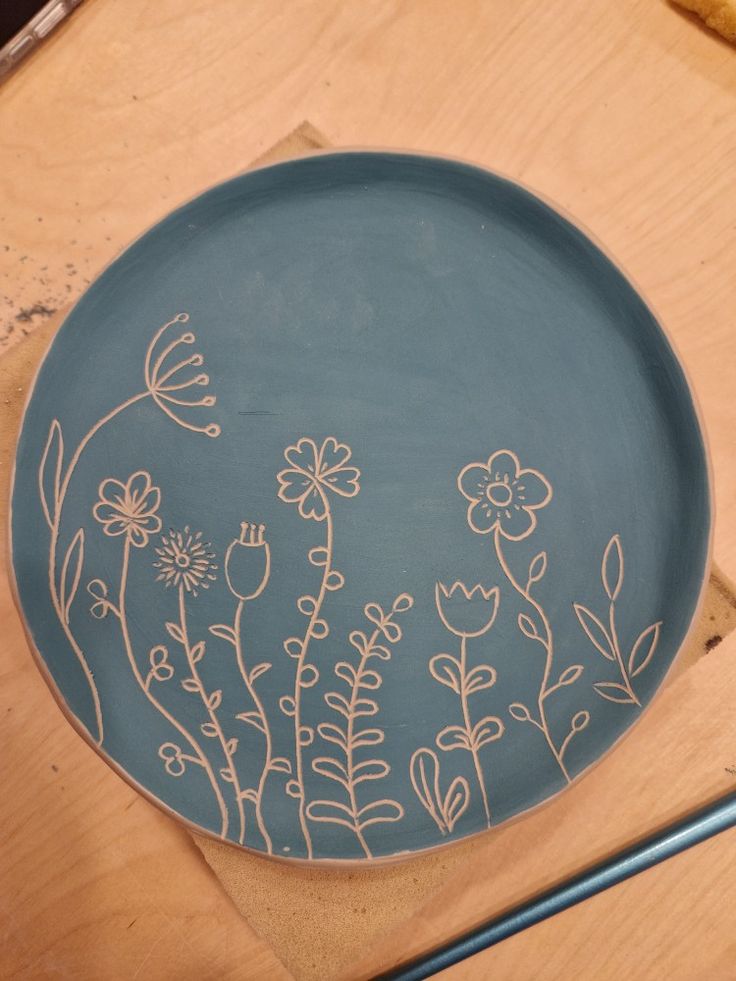 a blue plate with white flowers on it sitting on a table next to a pair of scissors