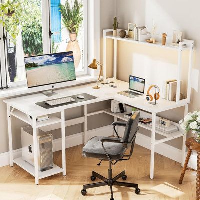 a desk with a computer on top of it in front of a window and potted plants