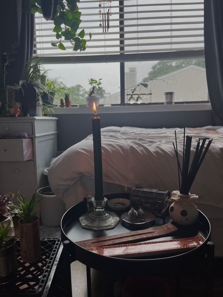 a round table with an old fashioned lit candle and incense on the table surface, with plants and rainy window background Burning Incense Aesthetic, Incense Aesthetic Bedroom, Incense Aesthetic, Plant Apartment, Burning Incense, Apartment Aesthetic, Cottage Core, Aesthetic Bedroom, New Room