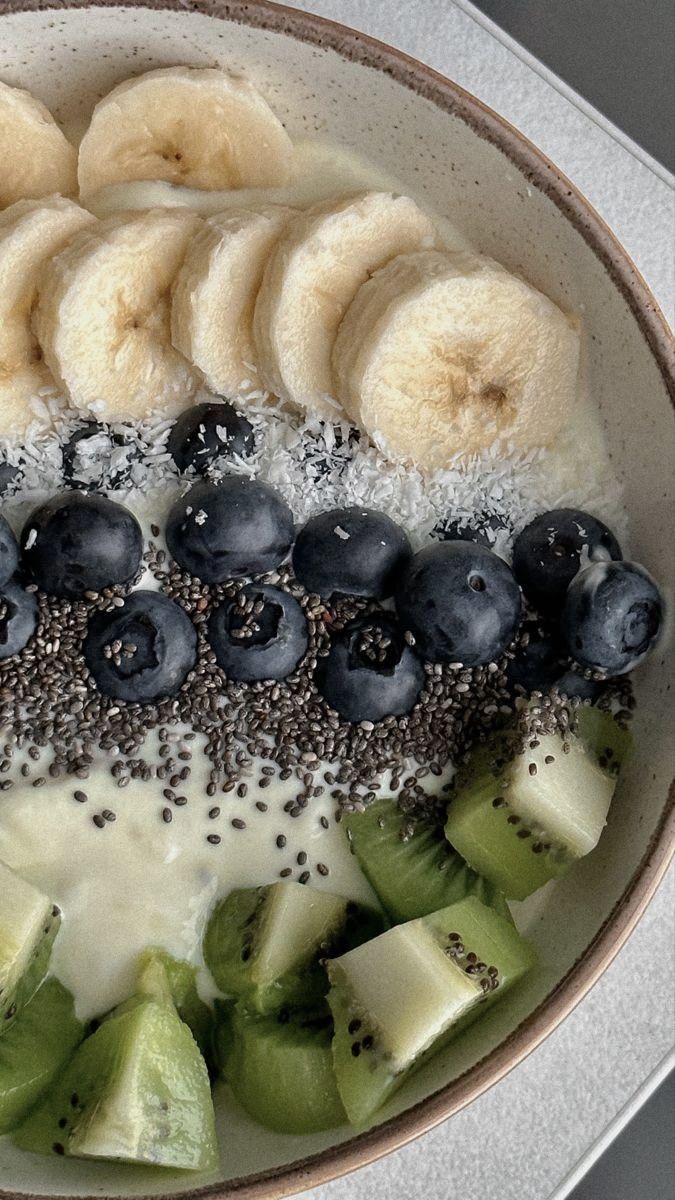 a bowl filled with bananas, kiwis and blueberries