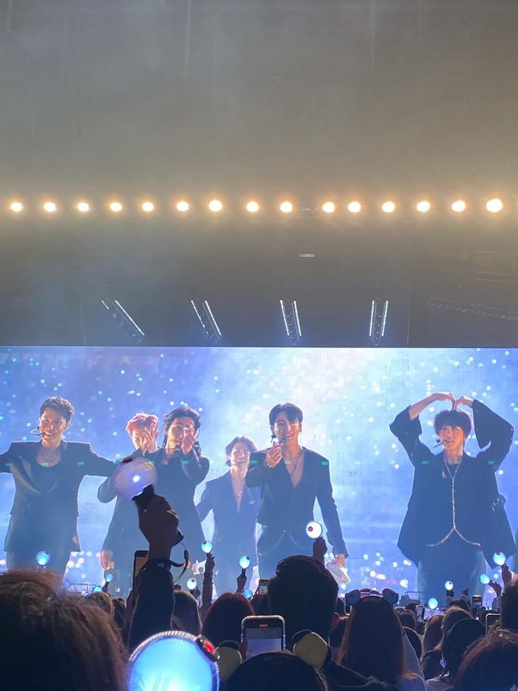 a group of men standing on top of a stage with their hands in the air