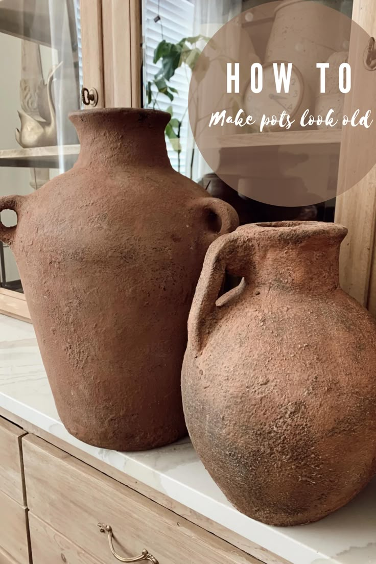 three clay vases sitting on top of a counter next to a clock and cabinet