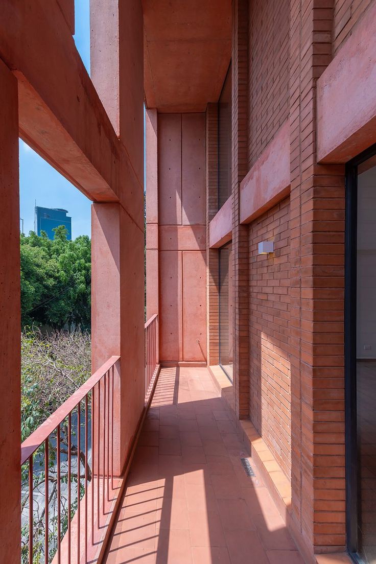 an empty corridor between two buildings with brick walls and balconies on either side