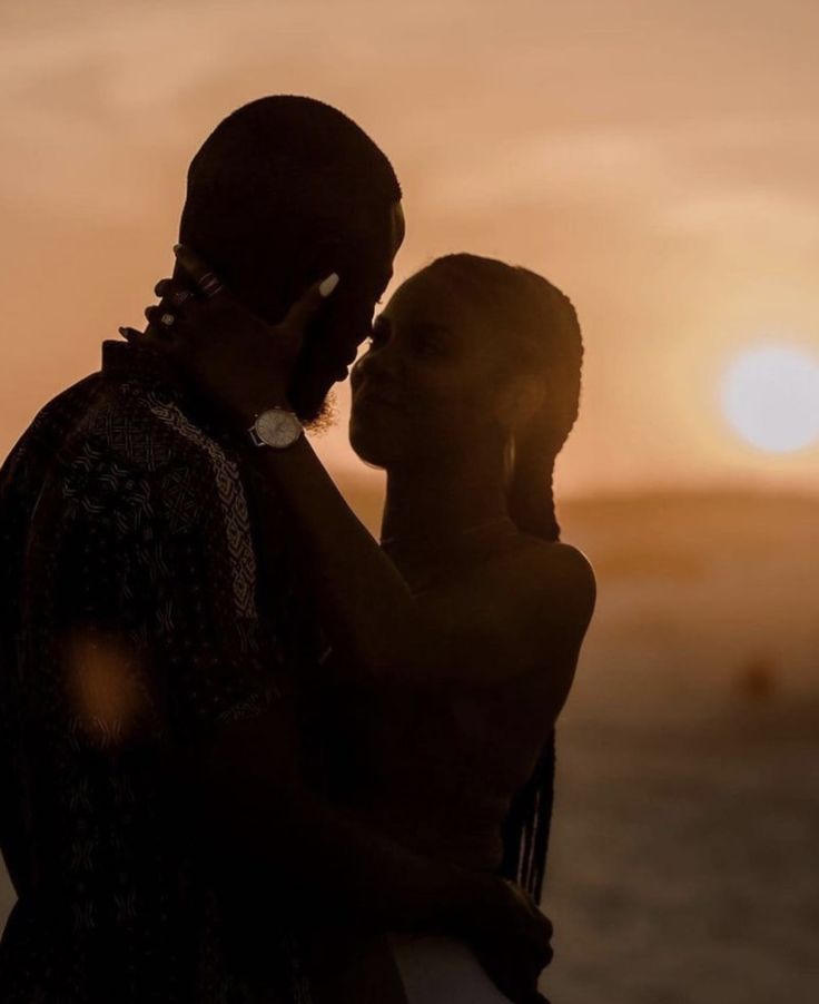 a man and woman standing next to each other at sunset