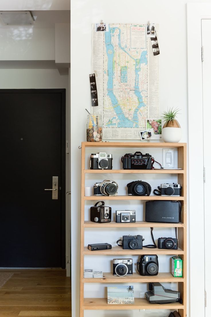 a wooden shelf filled with cameras next to a door