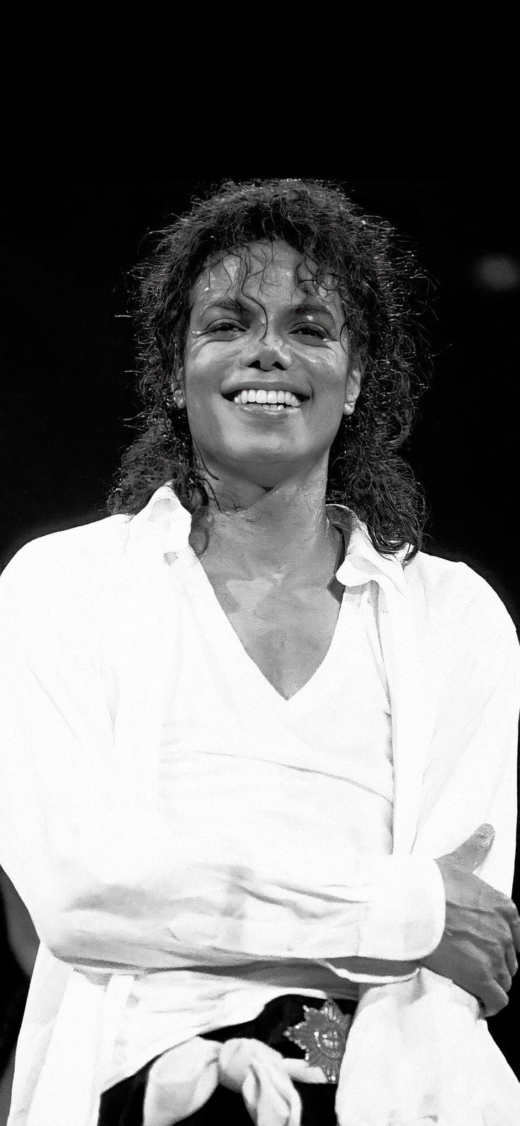 a black and white photo of a woman with her arms crossed, smiling at the camera