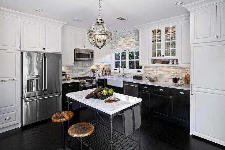 a kitchen with black and white cabinets, stainless steel appliances and an island in the middle