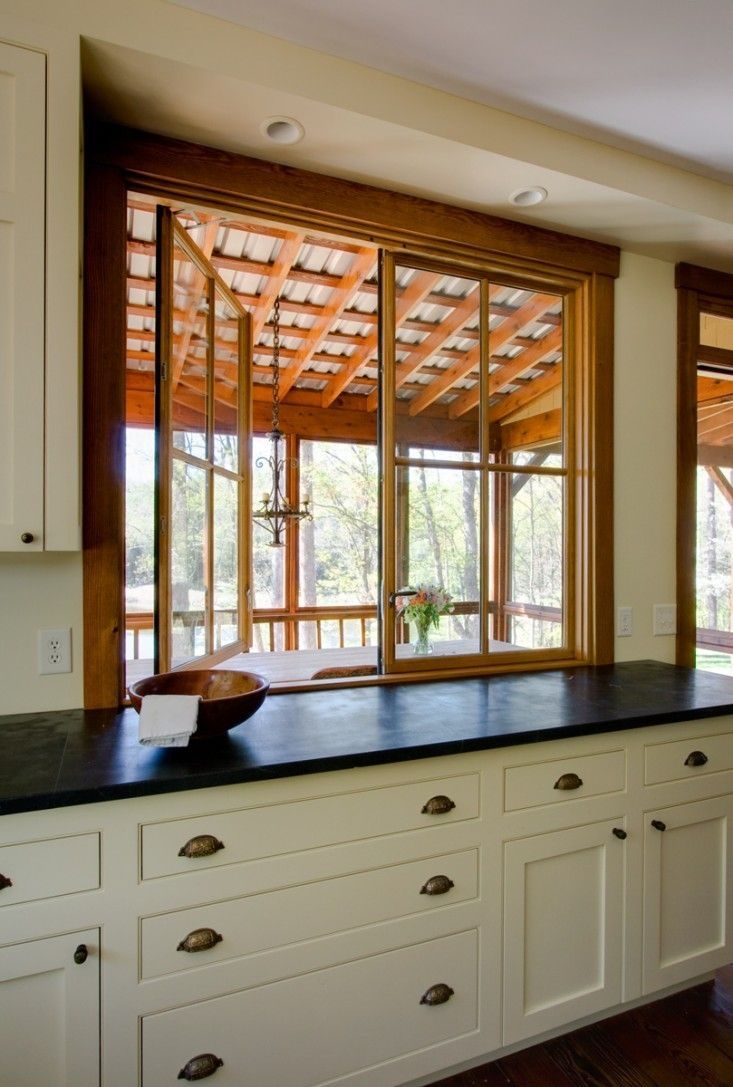 an empty kitchen with white cabinets and black counter tops is seen through the open windows