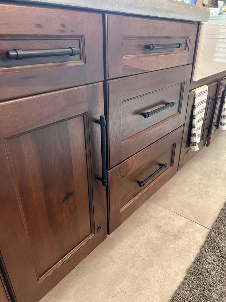 a kitchen with brown cabinets and black handles on the door knobs is seen in this image