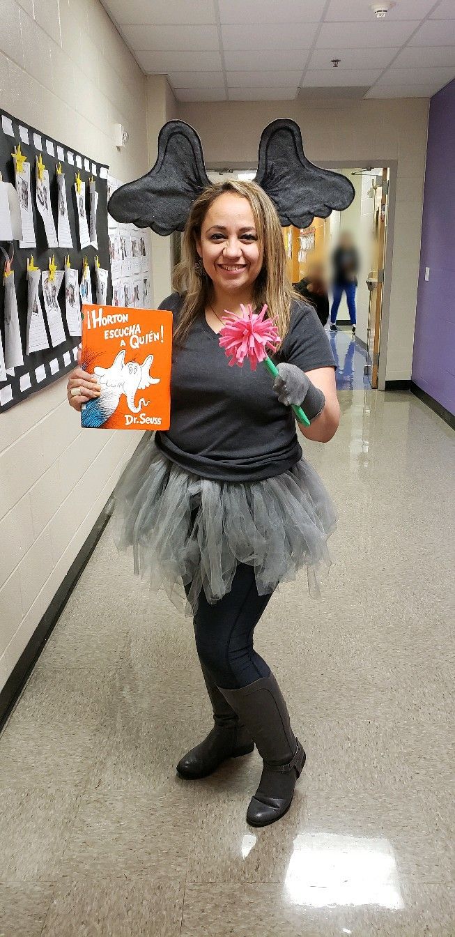 a girl is dressed up as a mouse holding an orange book with ears on her head