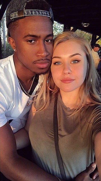 a man and woman are sitting in the back of a car looking at the camera