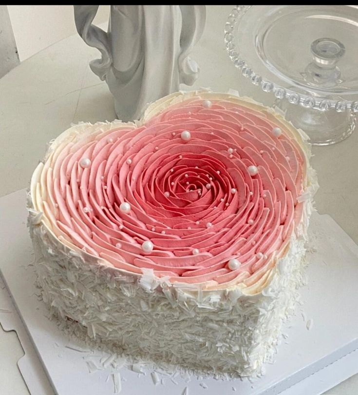 a heart shaped cake sitting on top of a white table next to a glass vase