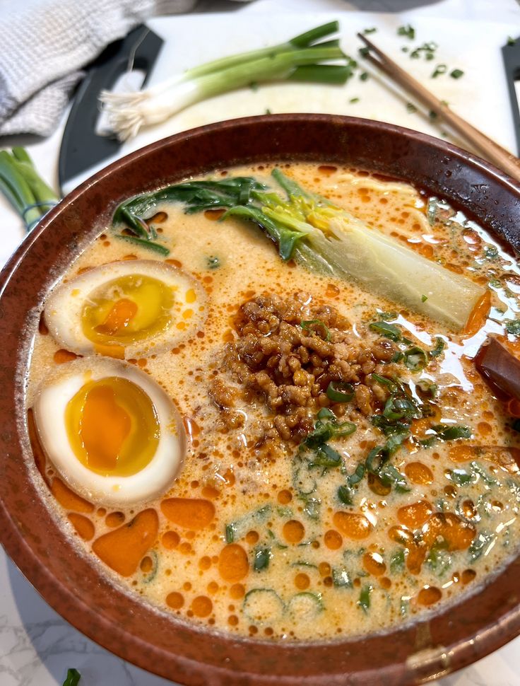 a bowl of soup with eggs, meat and vegetables