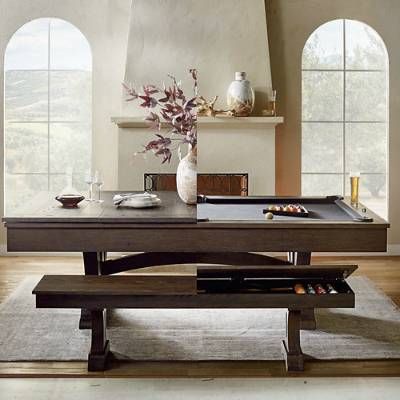 a pool table in the middle of a room with two windows and a vase on top