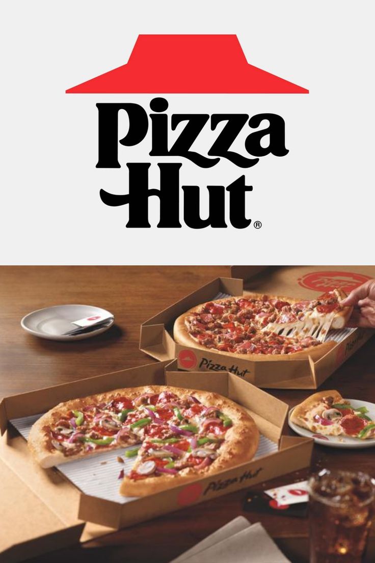 two pizzas sitting in boxes on top of a table next to a glass of soda