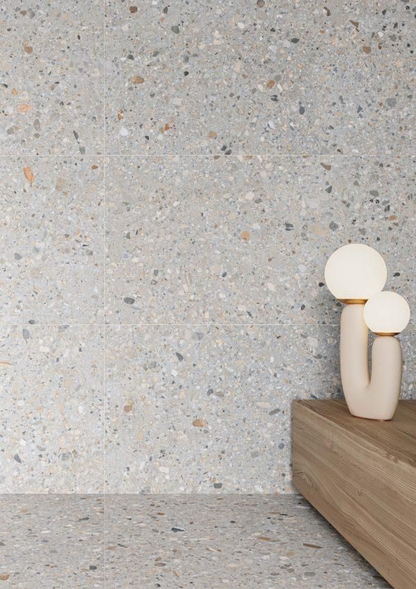 two white vases sitting on top of a wooden shelf next to a wall covered in speckled concrete