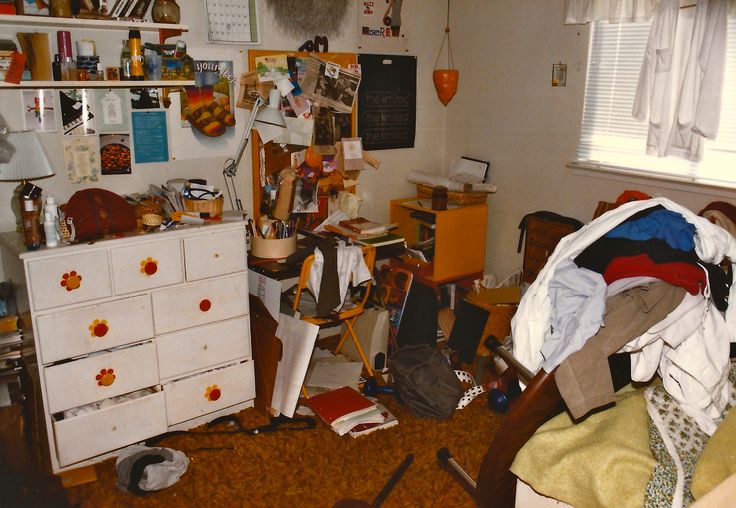 a messy bedroom with clothes and clutter on the floor