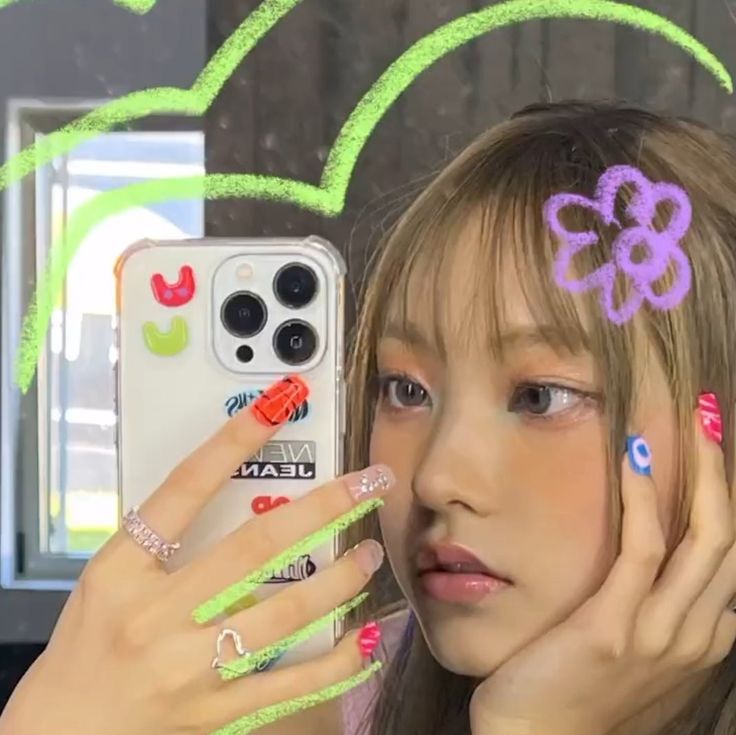 a young woman holding up her cell phone to her face while wearing neon nail polish