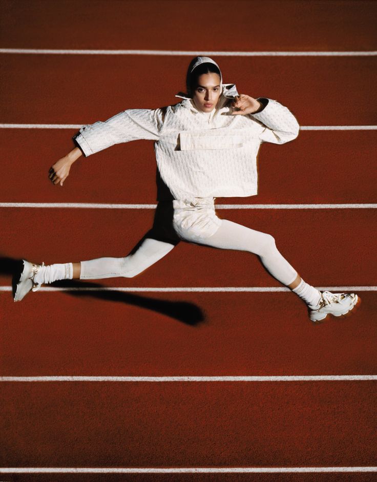 a man is running on a track with his hands in the air and wearing white