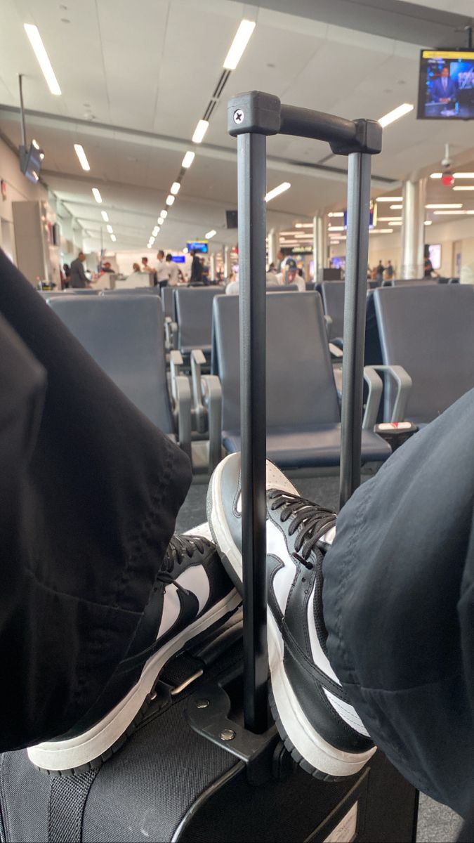 a person sitting in an airport with their feet up on the luggage bag and his legs crossed