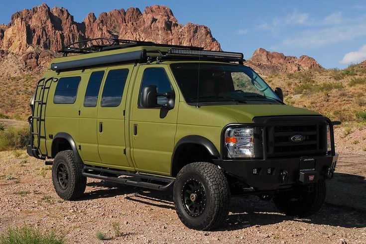 a green van parked in the desert with mountains in the background