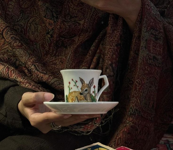 a woman holding a cup and saucer in her hands