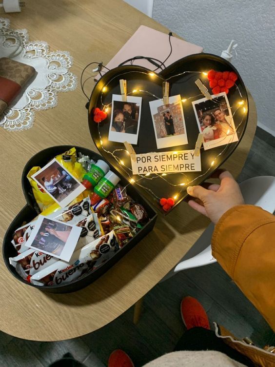 someone is holding a heart shaped box with photos and magnets on the inside it