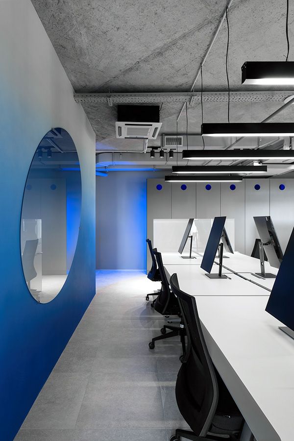 an office with blue and white walls, black chairs and desks in the middle