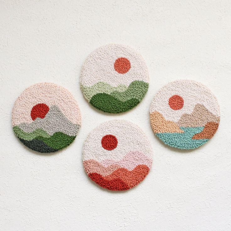 four coasters with different designs on them sitting next to each other in front of a white wall