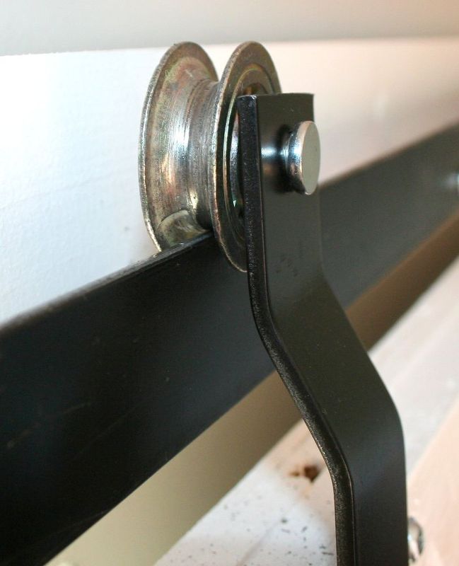 a close up of a black metal rail on a white bed with wood slats