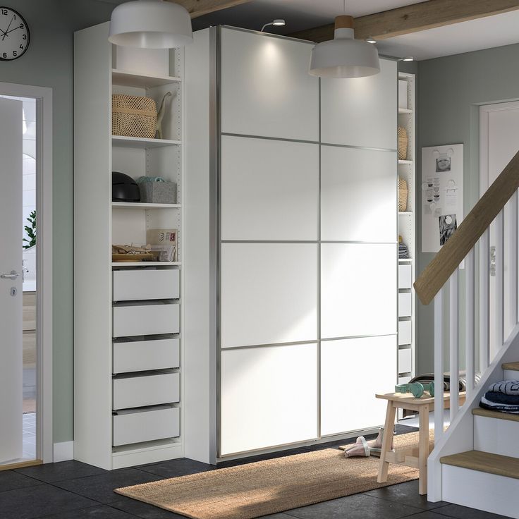 a white cabinet with drawers and shelves in a living room next to a stair case