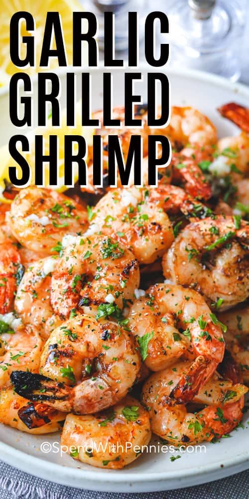 garlic grilled shrimp on a white plate with lemon wedges and parsley garnish