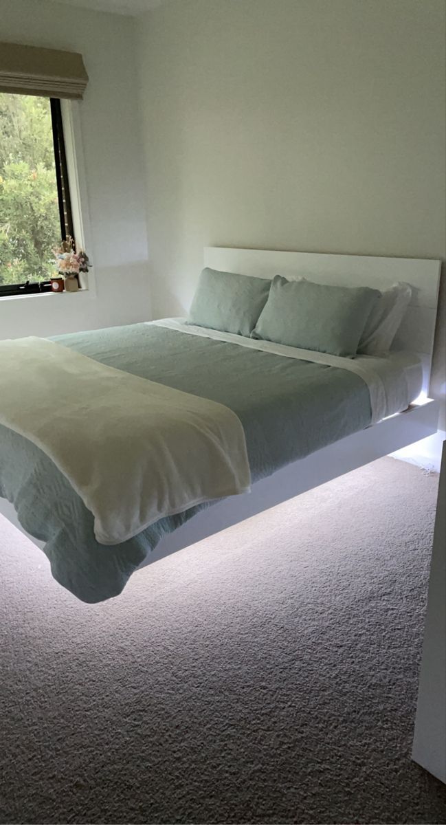 a bed sitting next to a window in a bedroom on top of a carpeted floor