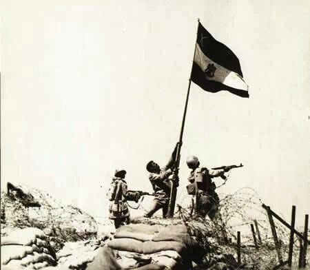 an old black and white photo of soldiers raising the flag on top of a hill