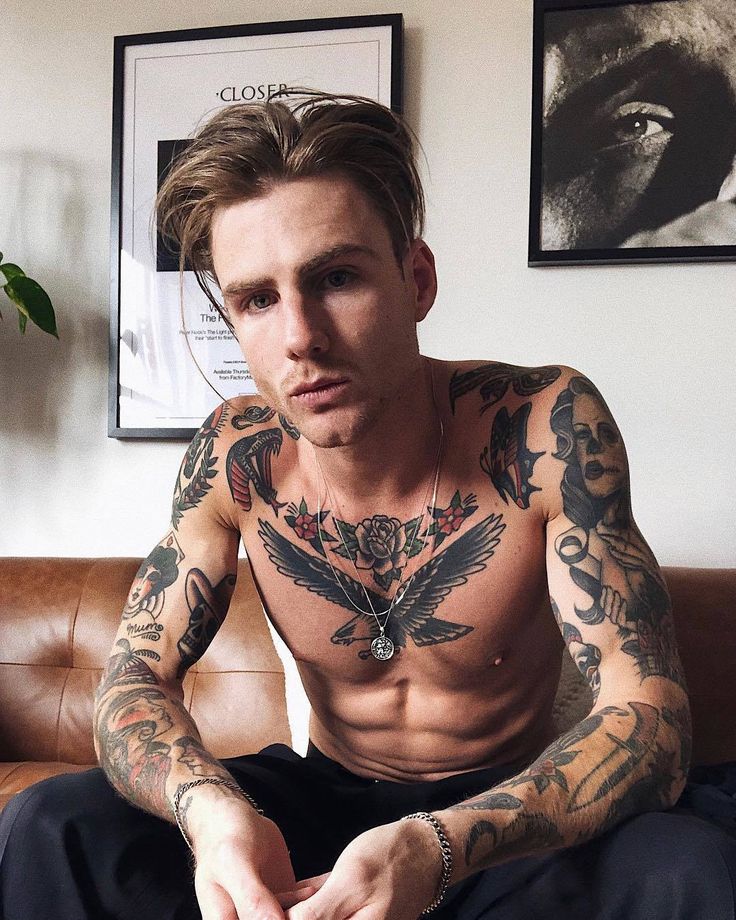 a man with tattoos sitting on a couch