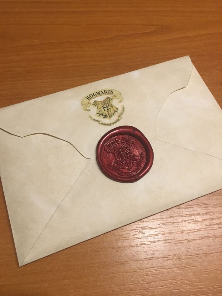 an envelope with a wax stamp on it sitting on top of a wooden table next to a seal