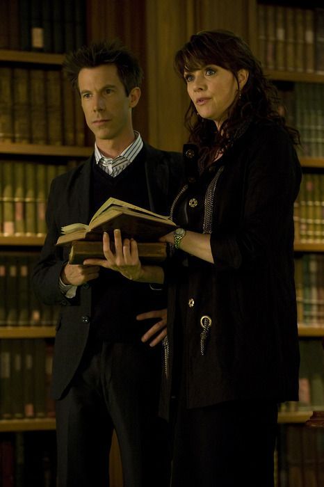 two people standing next to each other in front of bookshelves