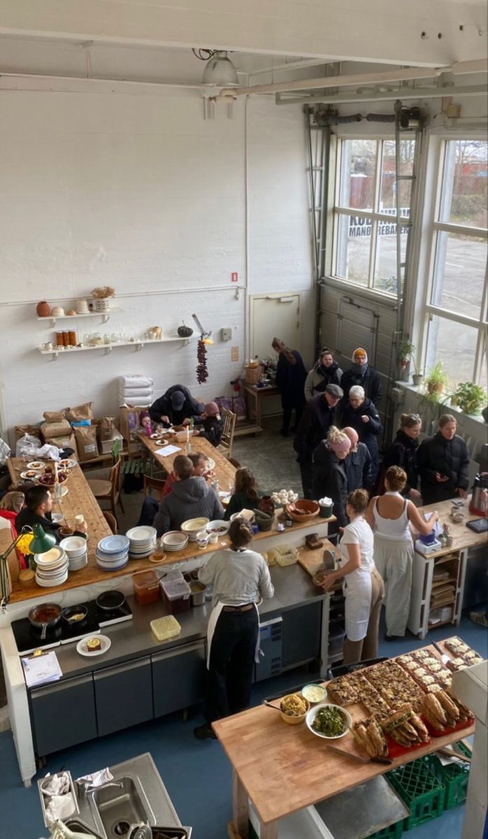 a group of people standing in a kitchen preparing food on top of a counter next to a window